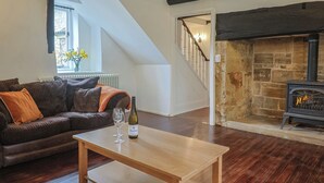 Un salon avec un canapé, une table, une bouteille de vin de Riesling, une cheminée et un escalier menant à une autre pièce.
