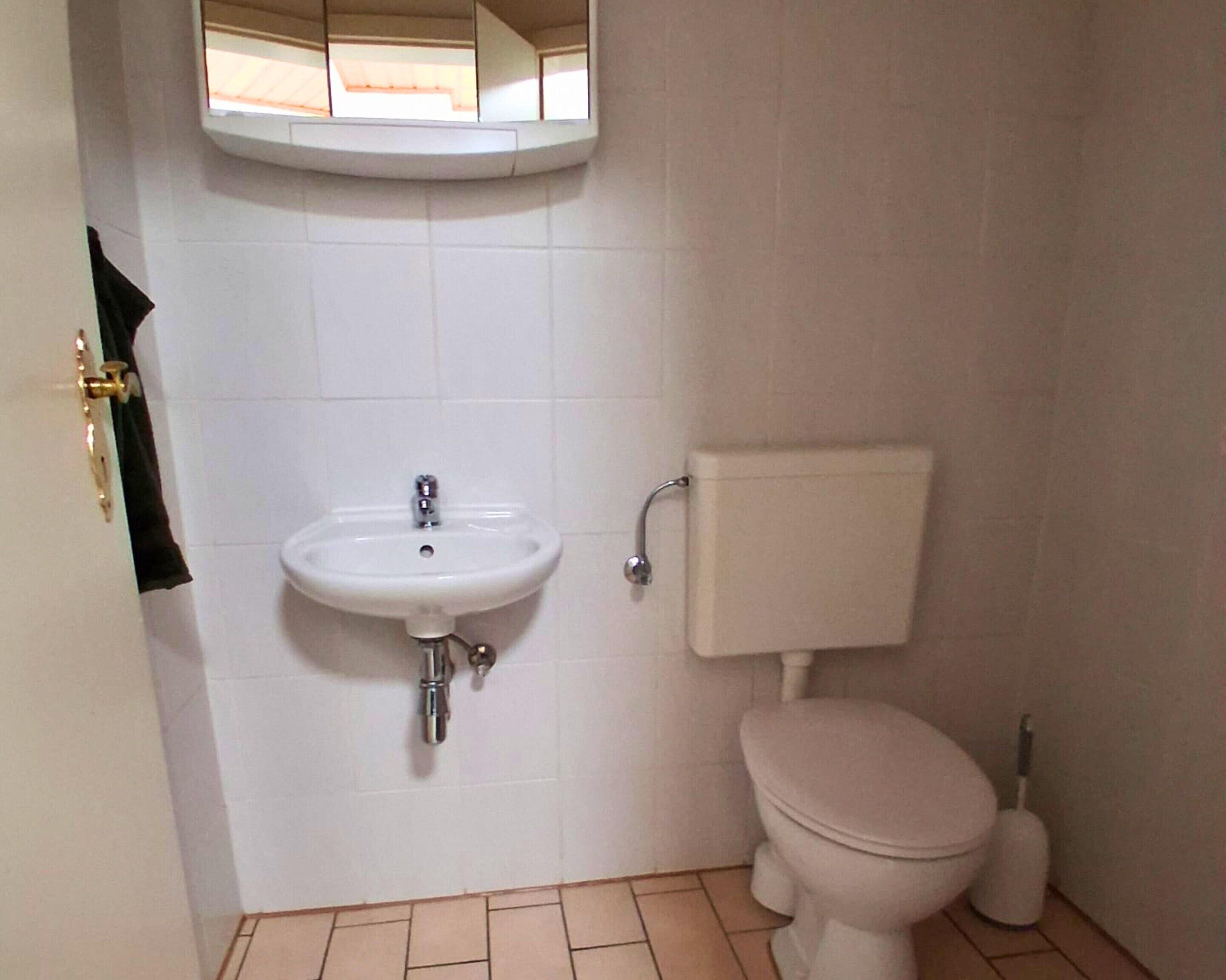 Un baño pequeño con un lavamanos blanco, inodoro y un espejo sobre el lavamanos.