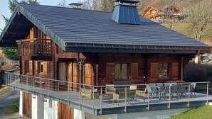 Uma cabana de madeira com varanda, área de estar coberta ao ar livre e vista para a paisagem circundante.