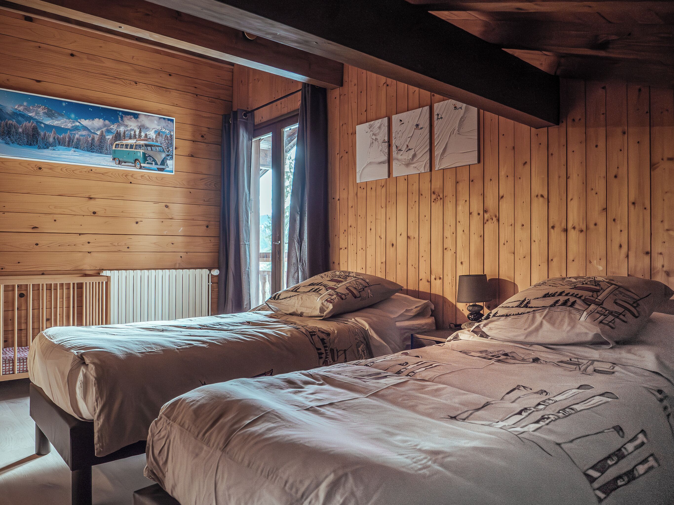 Ein gemütliches Blockhauszimmer mit zwei Betten, Holzwänden, einem Fenster mit Vorhängen und einem Bild an der Wand.