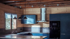 Uma cozinha moderna com paredes de madeira, uma bancada grande com banquetas, forno embutido e iluminação pendente.