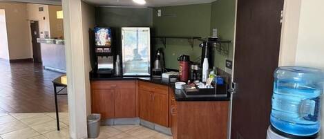 A small kitchenette with a coffee machine, a water dispenser, and a trash bin.