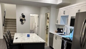Een moderne keuken met een centraal eiland, donker houten vloeren en roestvrijstalen apparatuur.