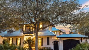 A large, two-story house with a balcony, a garage, and a well-maintained garden. - Home with Private Pool and Courtyard (Rosemary Beach)