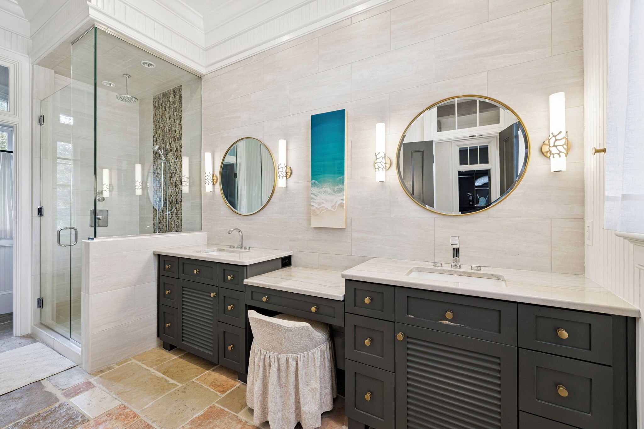 A modern bathroom with two sinks, dark cabinets, and a glass shower enclosure.