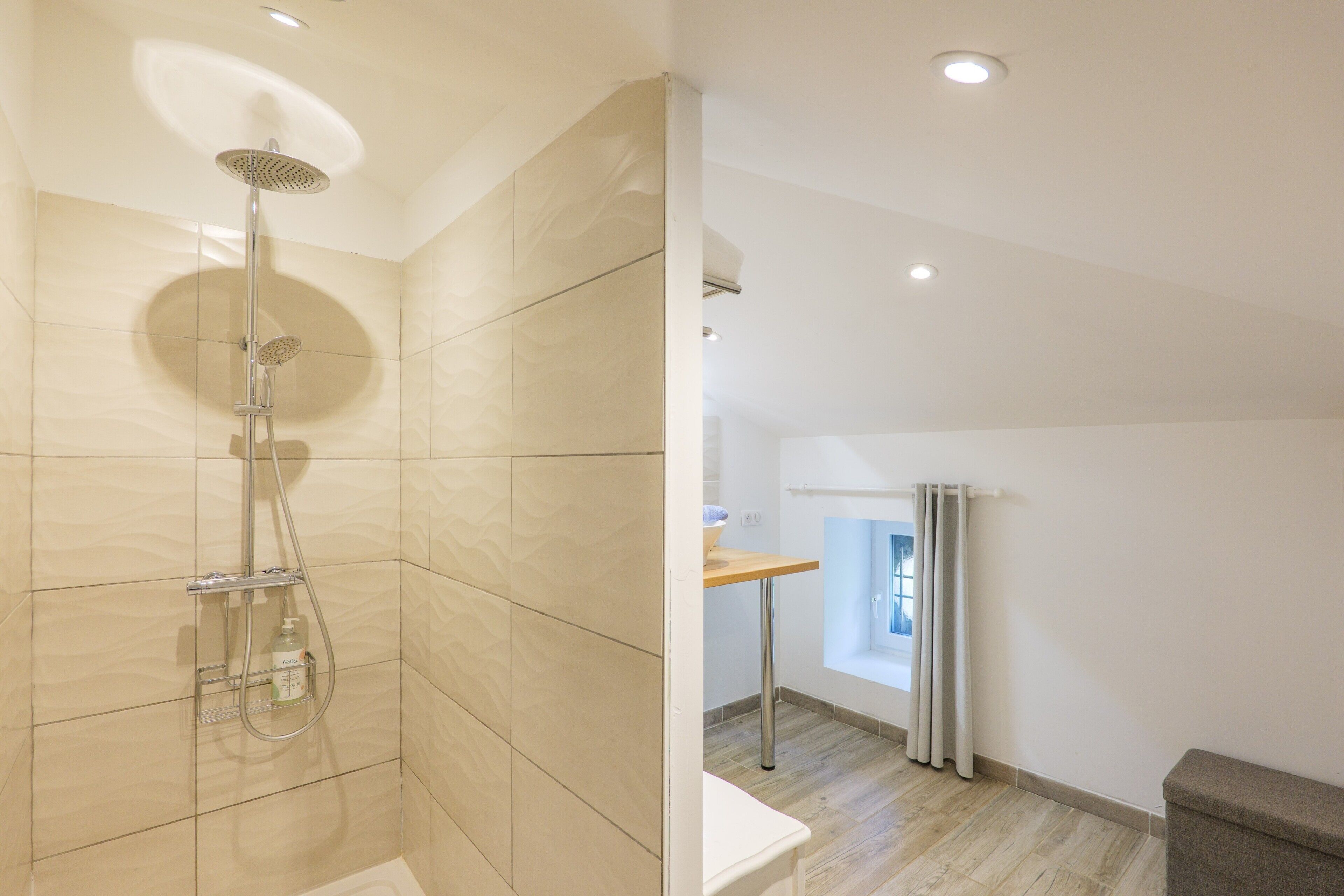 A modern bathroom with a shower, a sink, and a window with curtains.