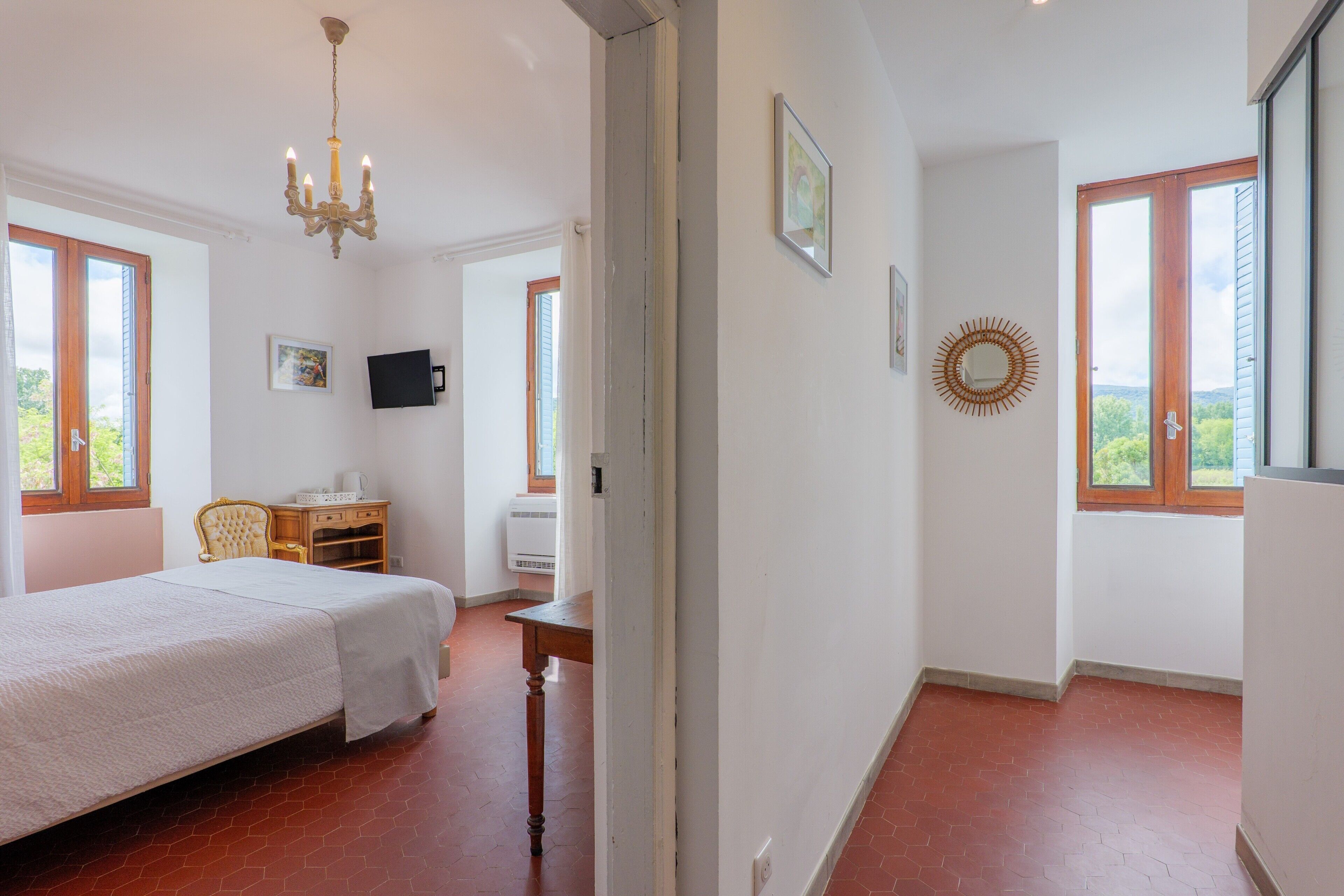 Une chambre à coucher avec un lit, un bureau, une chaise, une télévision et une fenêtre donnant sur un beau paysage.