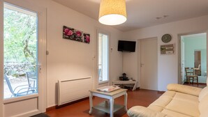 Una sala de estar con un sofá, una mesa, un televisor y una puerta que da al exterior.