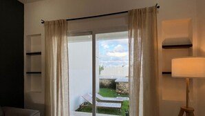 Una sala moderna con un ventanal corredizo que da a un patio con mobiliario exterior.