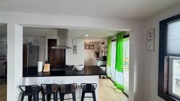 Una cucina moderna con isola centrale, sgabelli da bar e vista sull'esterno.