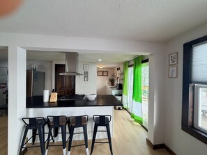 Eine moderne Küche mit einer zentralen Kochinsel, Barhocker und Blick ins Freie.