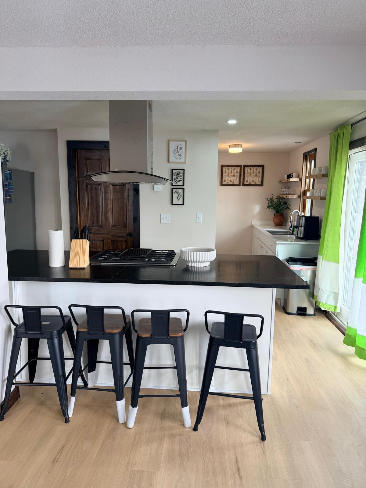 A modern kitchen with a central island, bar stools, and a dining area.