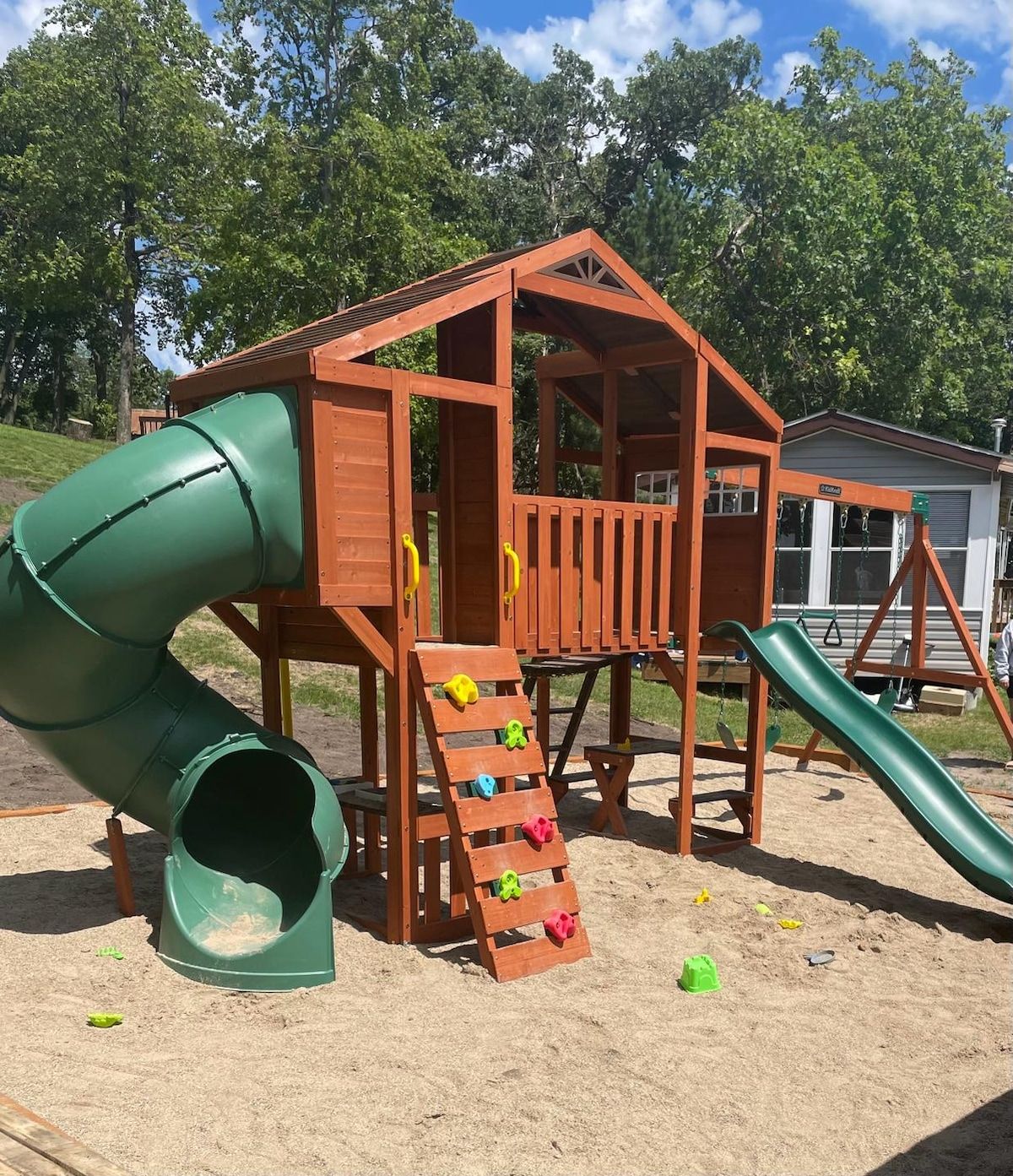 A wooden play structure with a slide and climbing steps.
