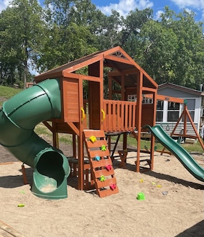 A wooden play structure with a slide and climbing steps.