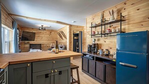 Une cuisine avec des murs en bois, un réfrigérateur bleu et un plan de travail en bois.