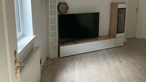 Una stanza con TV integrata, un armadietto in legno e un termosifone bianco.
