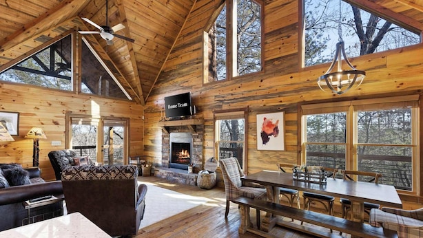A spacious log cabin interior with a fireplace, large windows, and a dining area. - Stunning Views! Sleeps 10 - Hot Tub - 2 Fireplaces (Blue Ridge)