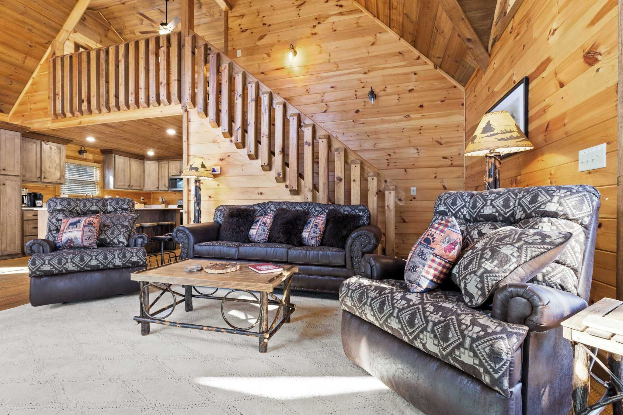 Un intérieur de chalet chaleureux avec un escalier en bois, un ensemble de canapés et une table à manger.