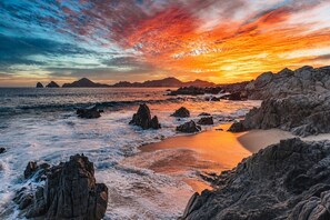 Eine Küstenlandschaft mit felsigem Gelände und einem Sonnenuntergang.
