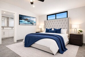 Une chambre moderne avec un grand lit, une tête de lit, deux tables de chevet avec des lampes, une commode, une grande fenêtre et un tableau au mur.