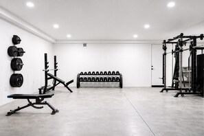 Une salle de sport équipée d’un banc de développé couché, d’un support à squats et d’haltères.