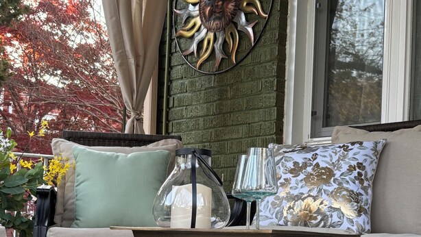 Uma área de estar acolhedora, com um sofá, um objeto decorativo na parede e uma mesa com base dourada.