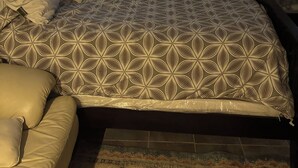 Um quarto com cama, janela com cortinas, um quadro na parede e mesa de cabeceira com abajur.