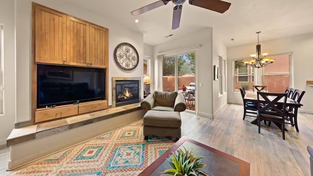 A spacious living room with a large TV, fireplace, and ceiling fan.