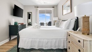 Et hotelværelse med seng, skrivebord, stol, fjernsyn, lampe og udsigt til det fri.