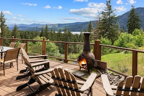 A deck with Adirondack chairs, a wood-burning stove, and a scenic mountain view.