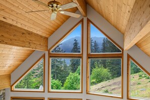 A room with a sloped ceiling, wooden beams, and large windows offering a view of a forested hillside. - Cle Elum Lake Cabin w/ Hot Tub & Game Room (Ronald)
