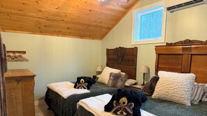 Ein gemütliches Schlafzimmer mit zwei Betten, einem Holzkopfende, einem Fenster mit Blick und einer Holzkammer.