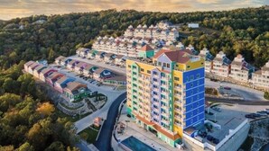 A multi-story hotel with a central courtyard, surrounded by lush greenery and a hilly landscape. - 2-bedroom condo, sleeps 6, in adorable Branson with cool AC and gym access. (Branson)