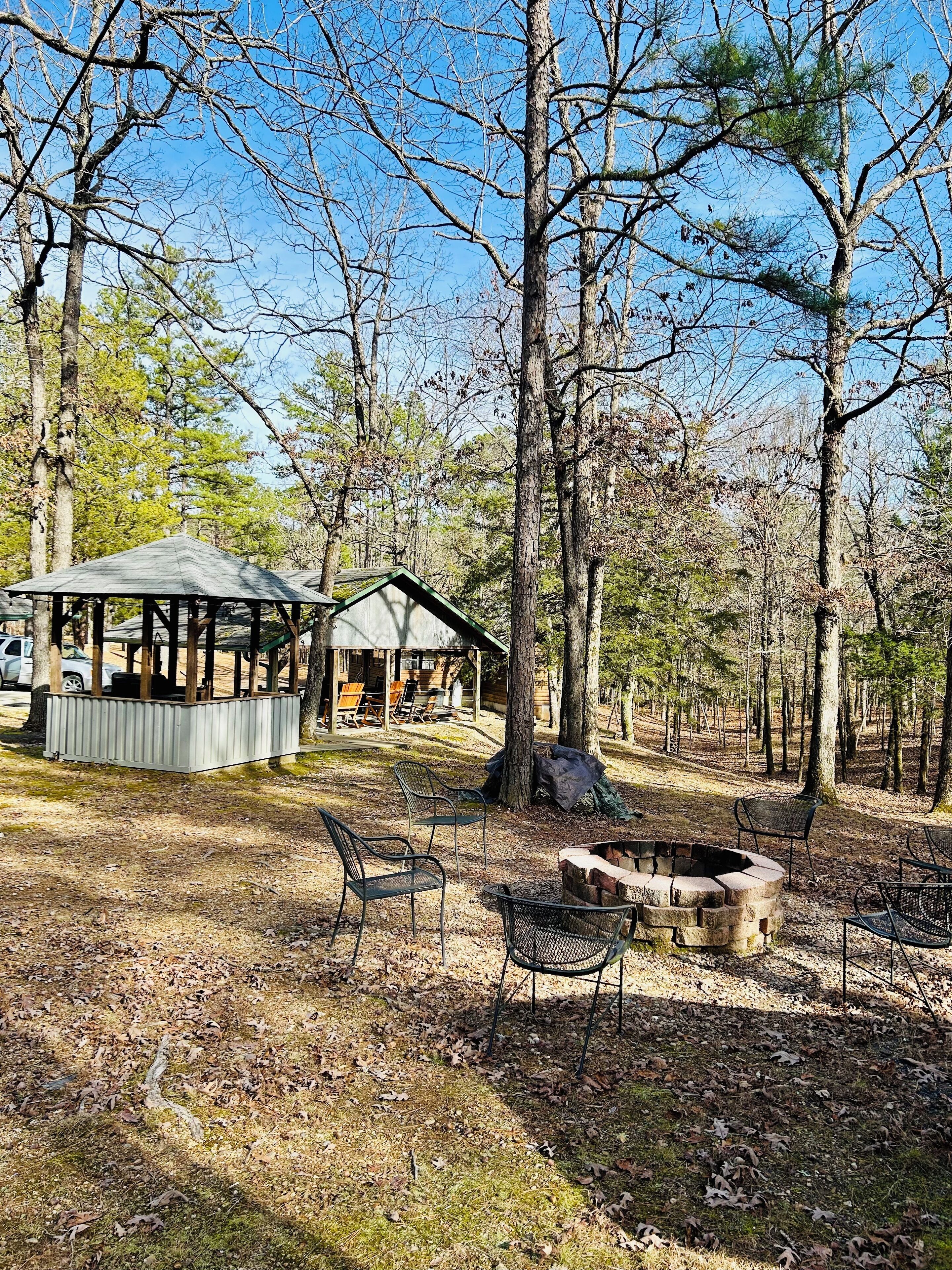 A rustic cabin with a covered porch and a fire pit area.