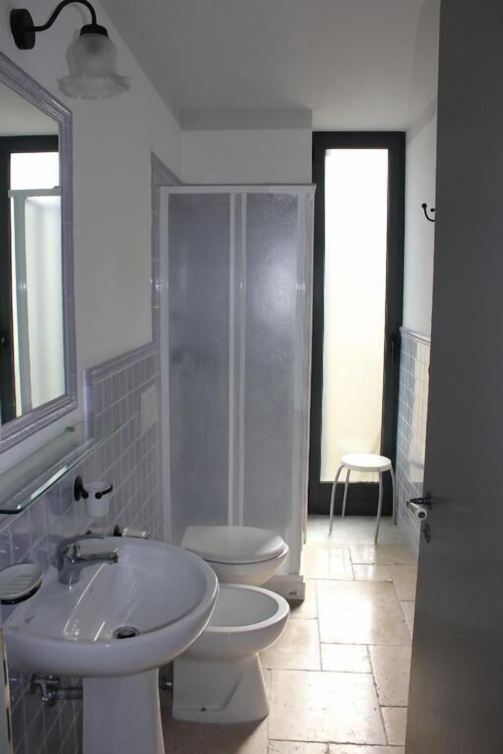 A bathroom with a sink, two toilets, and a shower.