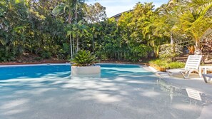 A swimming pool surrounded by lush tropical vegetation, with lounge chairs and a concrete deck. - Baden 2 - Rainbow Shores (Rainbow Beach)