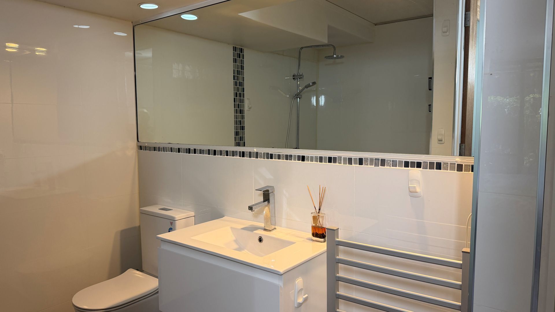Une salle de bain moderne équipée de toilettes, d’un lavabo et d’une douche.