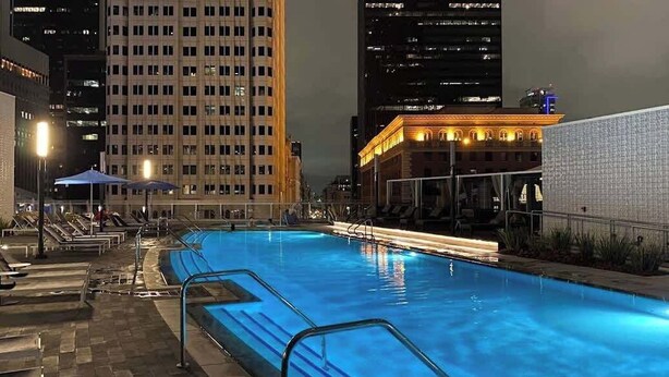 Ein Schwimmbecken bei Nacht mit Stadtgebäuden im Hintergrund.
