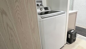 A compact laundry room with a front-loading washer and dryer, a small cabinet, and a power outlet. - Spacious 3 level 4-bedroom house- 2 Full kitchens-2 king beds and 3 queen beds. (Campbell)