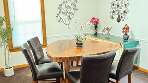 A dining area with a round wooden table, four black leather chairs, and decorative wall art. - Spacious 3 level 4-bedroom house- 2 Full kitchens-2 king beds and 3 queen beds. (Campbell)