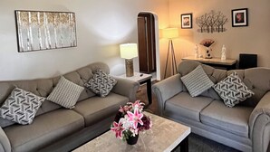 A living room with two sofas, a coffee table, a floor lamp, and wall art. - Spacious 3 level 4-bedroom house- 2 Full kitchens-2 king beds and 3 queen beds. (Campbell)