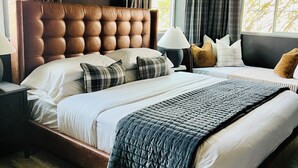 Un dormitorio moderno con una cama grande, cortinas oscuras y vistas a árboles a través de la ventana.