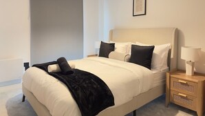 Ein modernes Schlafzimmer mit einem Bett, Nachttischen und einem Wandbild.