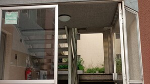 A building entrance with a glass door, a fire extinguisher, and a staircase leading to an upper floor. - Apartment steps from the subway and tourist sites (Santiago)