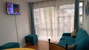 A living room with a teal sofa, a yellow table, and a TV on the wall. - Apartment steps from the subway and tourist sites (Santiago)