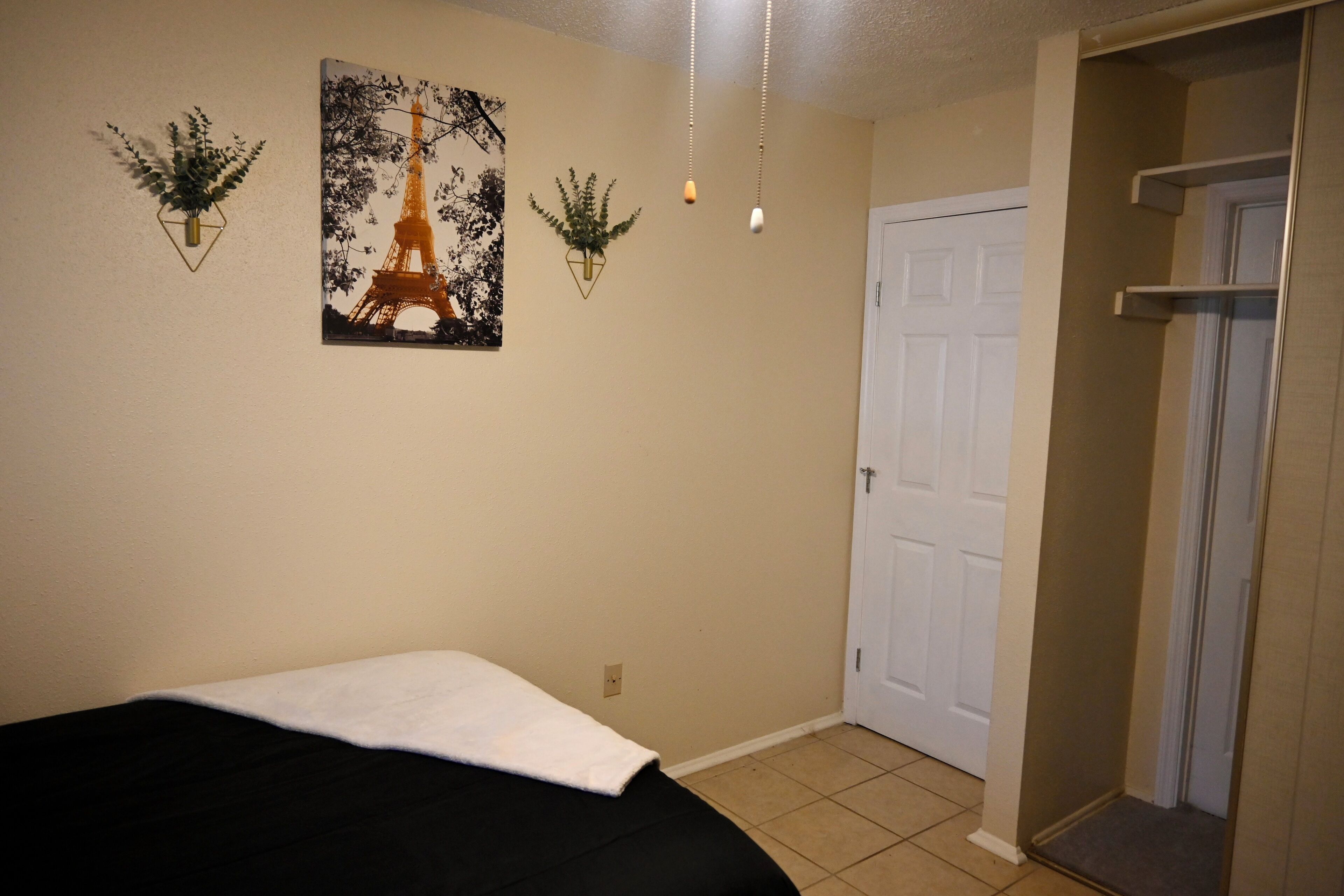 Un dormitorio con cama, una puerta y plantas en la pared.