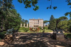 A large, classical building with a symmetrical facade, surrounded by a well-maintained garden with statues and a central fountain. - CASA-Elja Les Acacias avec piscine privée (Vidauban)