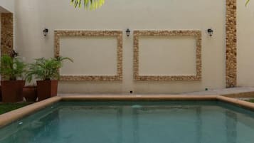 Ein Pool mit Steinverzierungen und Pflanzen in Töpfen.