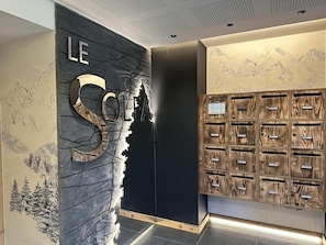 Ein Empfangsbereich mit einer Steinwand, einem großen 'LE'-Schild und einer Holzeinrichtung mit vielen Fächern.
