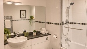 Un baño moderno con lavamanos, inodoro y ducha.